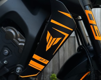 May include: A black motorcycle with orange and black accents. The motorcycle has a Yamaha logo and the text "MT" on the side.