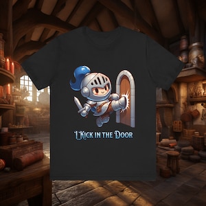 Op de afbeelding: Zwart t-shirt met een cartoon ridder die een deur intrapt. De ridder draagt zilveren harnas en een blauwe pluim. De tekst "I Kick in the Door" staat onder de afbeelding.