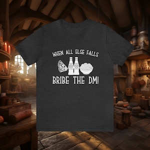 Op de afbeelding: Donkergrijs t-shirt met de witte tekst "WHEN ALL ELSE FALLS BRIBE THE DM!". Het ontwerp bevat pizza, twee flessen en een kom noedels. Een leuke grafische tee voor tabletop gamers.