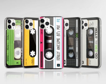 May include: Five different phone cases with a retro cassette tape design. The cases are all clear and show the phone's camera lens. The cassette tapes have different colors and designs, including pink, yellow, green, and black.
