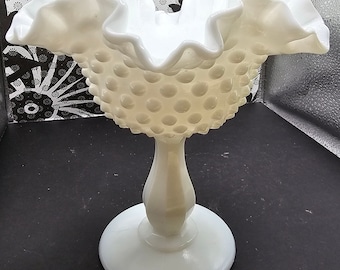 Puede incluir: Plato de dulces de vidrio de leche blanco con un borde rizado y una base de pedestal. El tazón está cubierto de pequeños puntos en relieve.