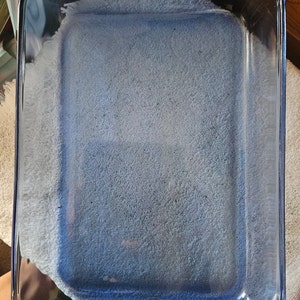 Könnte beinhalten: Eine blaue Glasbackform mit weißem Innenraum. Die Form ist leer und bereit zum Backen.