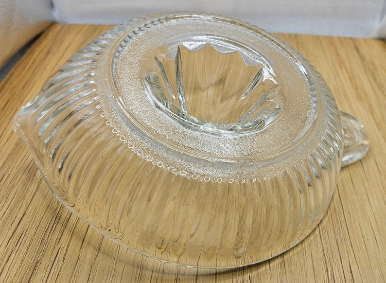 Puede incluir: Un exprimidor de c&iacute;tricos de vidrio transparente con un borde acanalado y un cono central para exprimir la fruta. El exprimidor tiene un peque&ntilde;o pico para verter el jugo.