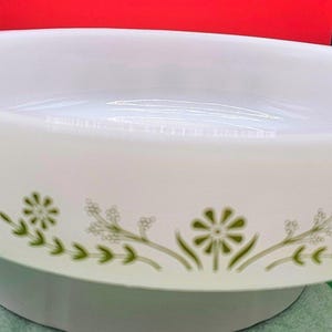 Peut inclure: Plat à gratin ovale blanc avec un motif floral vert sur le bord. Le plat a une finition lisse et brillante et est probablement en céramique ou en verre. Un classique pour la cuisson et le service.