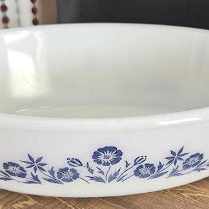 Peut inclure: Plat à four ovale blanc avec un motif floral bleu. Le plat a une finition lisse et brillante et un large bord avec des poignées. Le motif floral comprend des fleurs et des feuilles bleues. Un article de cuisine vintage.