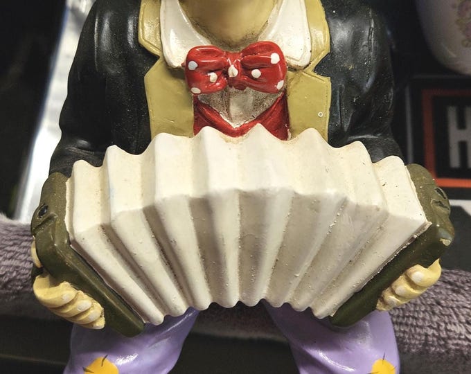 Discover a unique figurine of a melancholy clown gracefully playing the Aordion. C7/19