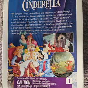 May include: A VHS tape featuring the Disney classic Cinderella. The cover features a colorful illustration of Cinderella, Prince Charming, and the mice Gus and Jaq. The text on the cover reads "Walt Disney's Masterpiece Cinderella". The back of the tape includes a safety warning and copyright information.