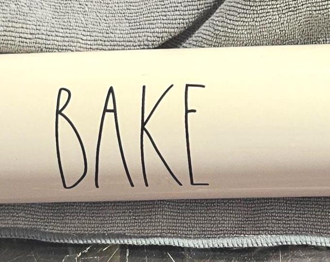 The Rae Dunn ceramic rolling pin by Magenta features the word "BAKE." RD3/14