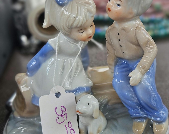 Vintage boy and girl with her puppy trying to give a sweet little girl.