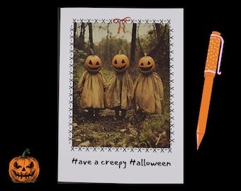 Pode incluir: Um cartão de felicitações de Halloween com uma foto de três figuras de abóbora em um ambiente de floresta. O cartão tem uma borda costurada em preto e branco e o texto "Have a creepy Halloween".