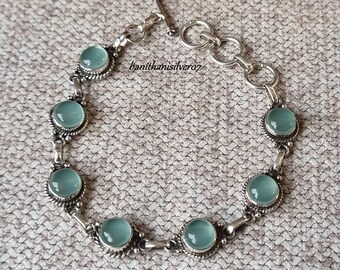 May include: Silver bracelet with a toggle clasp and six round, light blue gemstones.