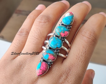May include: A silver ring featuring five turquoise and pink stone settings. The ring has a vertical design with a series of oval and teardrop-shaped stones. The ring is on a hand. The text "SilverJewellery2025" is visible.