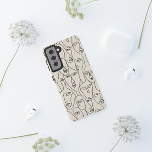 May include: A beige phone case featuring a repeating pattern of abstract line-drawn faces in black. The phone case is surrounded by white accessories, including wireless earbuds and a charging case, set against a white background.