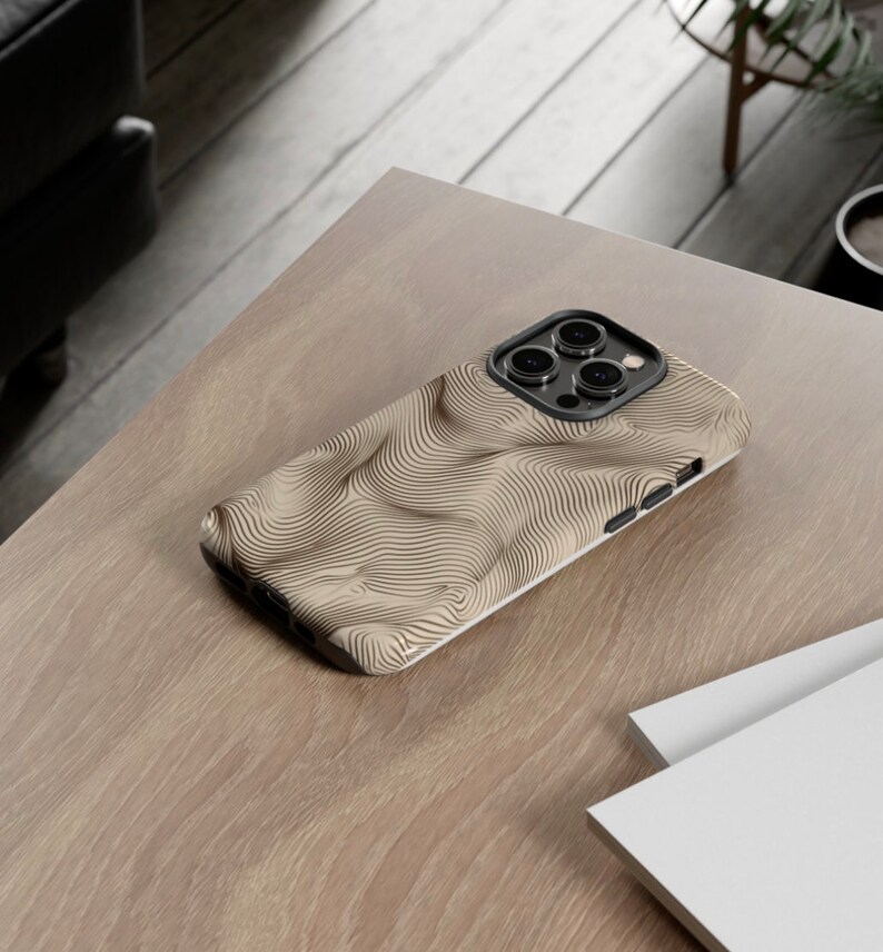 May include: A beige phone case with a black and white wavy pattern. The case has a raised camera bump with three lenses.