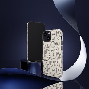 May include: A smartphone and a phone case with a cream-colored background. The case features a repeating pattern of abstract line-drawn faces in black. The smartphone is black and has a sleek design. The background is a dark blue with a white ribbon.