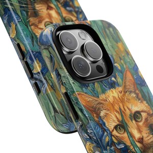 May include: A phone case featuring a painting of a ginger cat amidst blue and yellow flowers. The case has a black camera lens protector and a glossy finish. The artwork resembles a Van Gogh style painting.