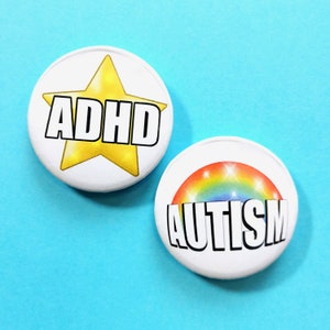 Peut inclure: Deux badges ronds blancs avec du texte noir et des graphismes colorés. Le premier badge présente une étoile jaune avec le texte "ADHD". Le deuxième badge présente un arc-en-ciel avec le texte "AUTISM".