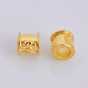 Può includere: Due distanziatori per perline in metallo dorato con un design floreale. I distanziatori sono cilindrici e hanno una finitura liscia e lucida.