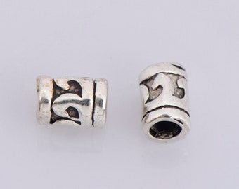 May include: Two silver metal beads with an intricate design. The beads are cylindrical and have a smooth, polished finish.
