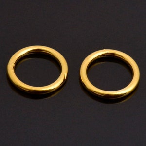 May include: Two gold-coloured hoop earrings. The hoops are simple and circular.