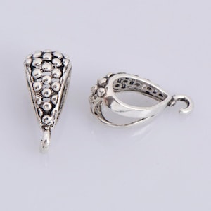 May include: Two silver-toned pendant bails with a textured design. One bail is a teardrop shape with a loop at the top. The other bail is a triangular shape with a loop at the bottom.
