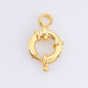 Puede incluir: Cierre de metal dorado con un anillo redondo y una pequeña bola en la parte inferior.