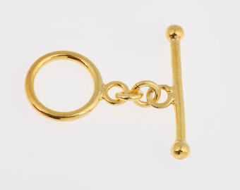 May include: Gold-toned metal toggle clasp with a round ring and a straight bar with rounded ends.