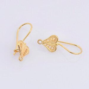 May include: A pair of gold filigree heart-shaped earrings with a hook closure.