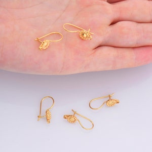 May include: Four gold-toned earring hooks with a small, round, textured design at the end of each hook.
