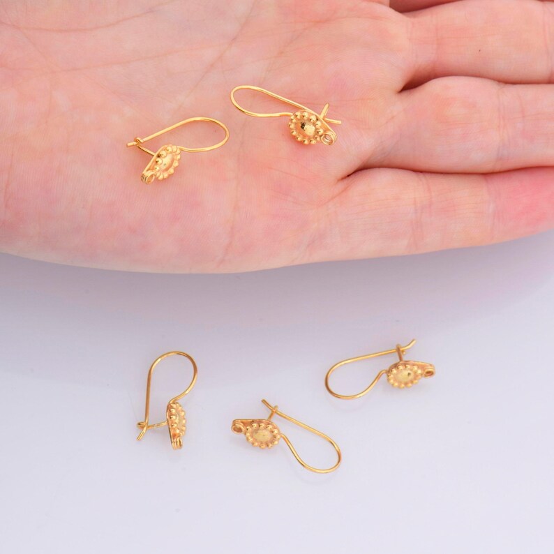 May include: Four gold-toned earring hooks with a small, round, textured design at the end of each hook.