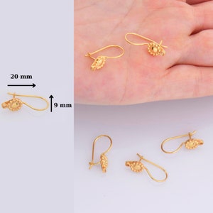 May include: Gold-toned earring findings with a small, round, textured design. The findings are 20 mm long and 9 mm wide.