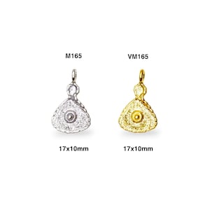 May include: Two silver and gold pendants in the shape of a dress with a small round bead in the center. The pendants are 17mm x 10mm. The silver pendant is labeled M165 and the gold pendant is labeled VM165.