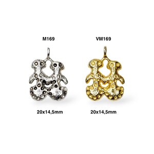 May include: Two silver and gold pendants in the shape of two people holding hands. The pendants are 20x14.5mm in size. The silver pendant is labeled M169 and the gold pendant is labeled VM169.