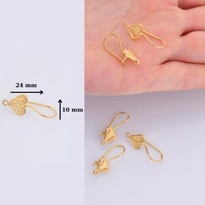 May include: Gold-tone filigree earring hooks, measuring 24 mm long and 10 mm wide. The hooks are shaped like a heart with a delicate, intricate design.