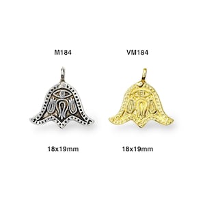 May include: Two pendants, one silver and one gold, with a stylized eye and floral design. Both pendants are 18x19mm.