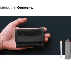 Bester und kleinster Tabakbeutel, präsentiert auf Handfläche. Im Größenverhältnis zu einem Feuer und einer Zigarette sowie Hand dargestellt. SMAROG Handmade in Germany