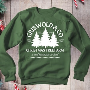 May include: Green sweatshirt with a white design that says "Griswold & Co. Christmas Tree Farm, Est. 1989, a real beaut guaranteed". The design features three stylized Christmas trees.