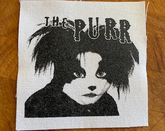 May include: Black and white iron-on patch with a cartoon image of a cat with the text "THE PURR" above it.