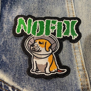 May include: Green embroidered patch with the word "NOFX" in a jagged font. Below the word is a cartoon image of a dog wearing a cone of shame.