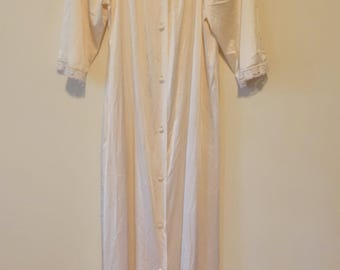 May include: A floor-length cream-colored nightgown featuring long sleeves with lace-trimmed cuffs, a square neckline adorned with intricate lace detailing, and a full-length front button closure with matching cream-colored buttons.