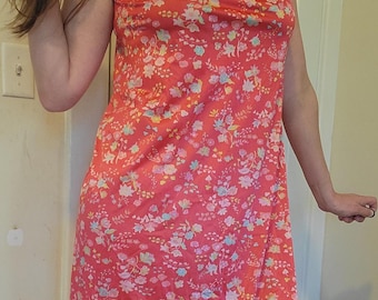 May include: A sleeveless, red dress with a floral print. The dress has a V-neck and a loose fit.