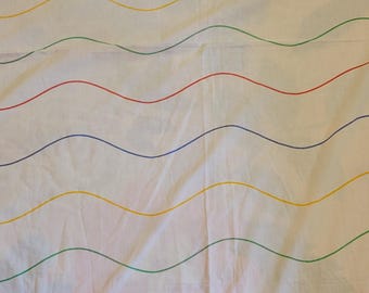 Sábana bajera ajustable de estilo vintage con colores primarios y líneas onduladas.