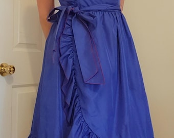 May include: A vibrant blue midi dress featuring thin spaghetti straps, a wrap-style bodice with a ruffled edge, and a matching ruffled hemline. The dress includes a fabric tie at the waist and is accented with thin, dark purple piping along the ruffles.