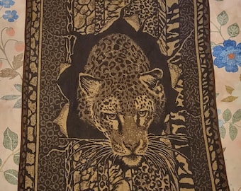 May include: A rectangular woven tapestry featuring a central leopard head emerging from a dark, torn-effect background. The design is framed by vertical panels of various animal print patterns in shades of dark brown, tan, and black.