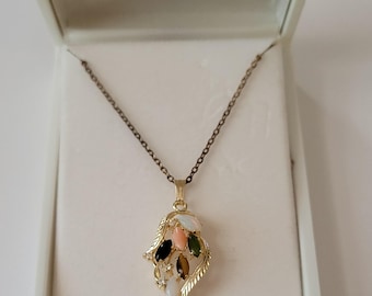 May include: A gold-tone necklace featuring a pendant with a leaf-shaped frame. The pendant is set with multiple marquise-cut stones in shades of white, pink, dark green, and brown, accented by small clear stones, suspended on a thin metal chain.