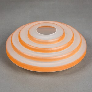 May include: A white frosted glass lampshade with four concentric orange rings.
