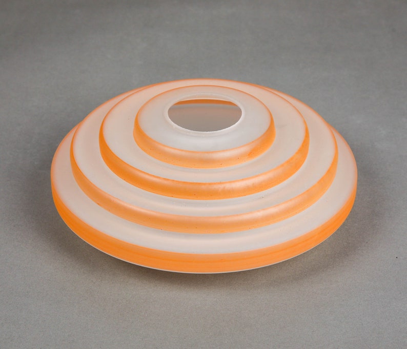 May include: A white frosted glass lampshade with four concentric orange rings.