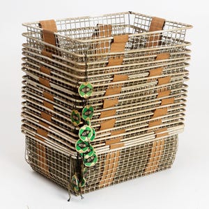 Op de afbeelding: Een stapel rechthoekige draadmandjes met houten accenten. Elke mand heeft een rasterpatroon en is gemaakt van een lichtgekleurd metaal. Groene en witte labels zijn aan de zijkant van de stapel bevestigd.