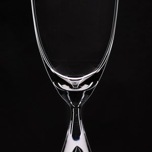 May include: A clear glass wine glass with a unique teardrop-shaped base.