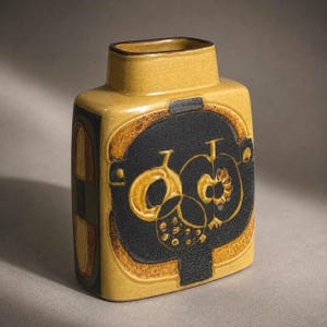 May include: A rectangular ceramic vase with a mustard yellow glaze. The vase features a black central design with gold-colored abstract shapes. The sides have a geometric pattern in shades of brown, green, and yellow. The vase has a rectangular opening.